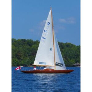 Vintage 1957 Dragon 29 sailboat on a lake with Canadian flag, clear blue sky.