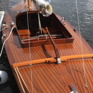 Vintage 1957 Dragon 29 sailboat with wooden deck, docked by the water.