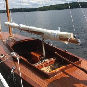 Vintage 1957 Dragon 29 sailboat with wooden deck, docked by a serene lake.