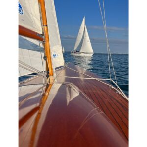 Vintage 1957 Dragon 29 sailboat on calm sea, showcasing polished wooden deck and sails.